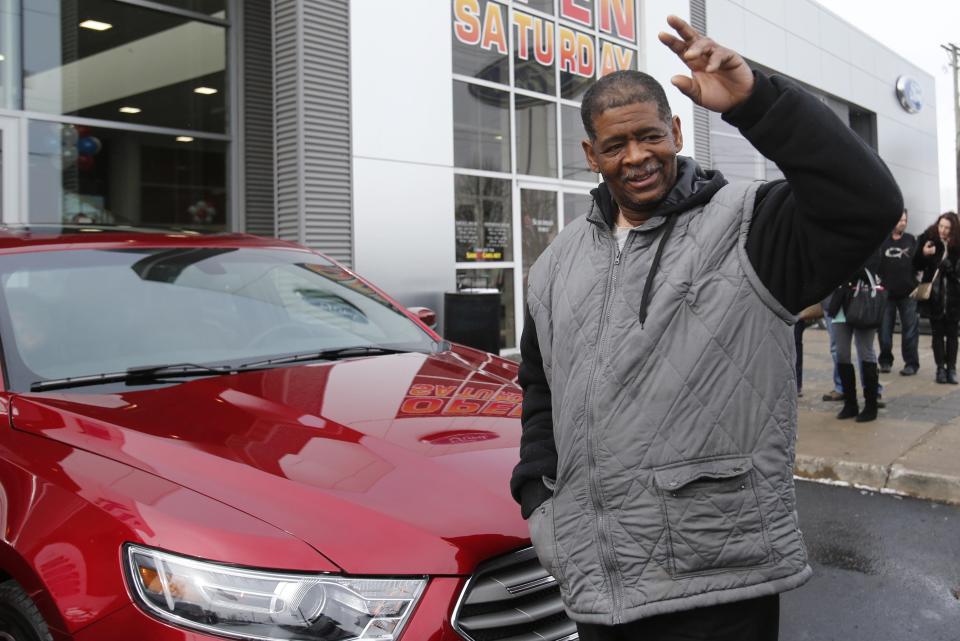 Detroit resident James Robertson waves to the crowd after being surprised with the free gift of a 2015 red Ford Taurus sedan, at the Suburban Ford dealership in Sterling Heights, Michigan, February 6, 2015. The 56-year-old factory worker, known for walking 21 miles to get to and from work for 9 years, is also the recipient of about $300,000 in donations raised by a college student after his story was widely publicized in local media. REUTERS/Rebecca Cook (UNITED STATES - Tags: TRANSPORT SOCIETY)