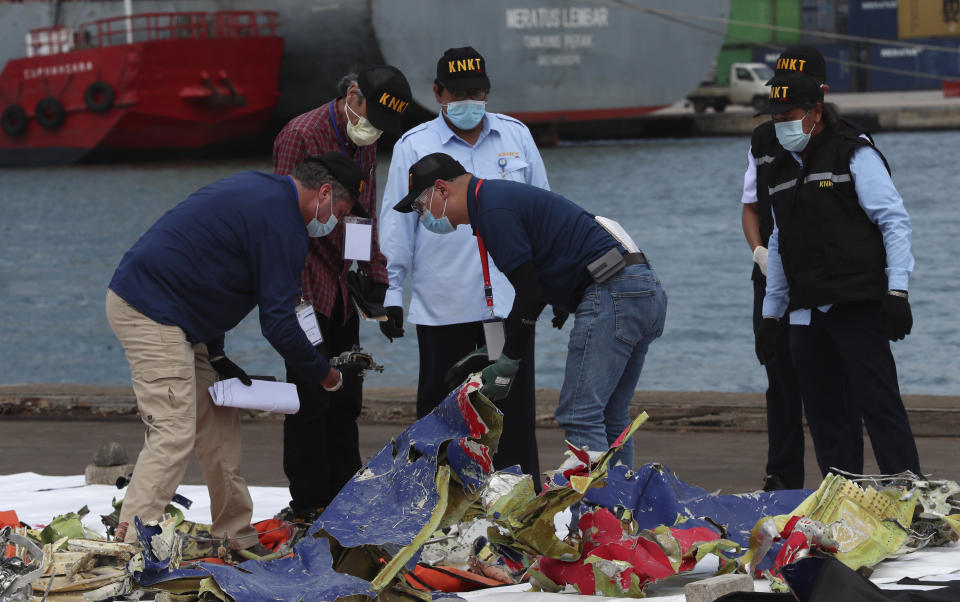 Members of the Indonesia's National Transportation Safety Committee (KNKT) and U.S. National Transportation Safety Board (NTSB) investigators team inspect debris found in the waters around the location where a Sriwijaya Air passenger jet crashed, at the search and rescue command center at Tanjung Priok Port in Jakarta, Indonesia, Saturday, Jan 16, 2021. (AP Photo/Achmad Ibrahim)