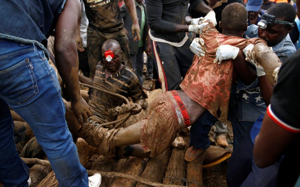 A rescued artisanal miner is carried from a pit as retrieval efforts proceed for trapped illegal gold miners in Kadoma, Zimbabwe