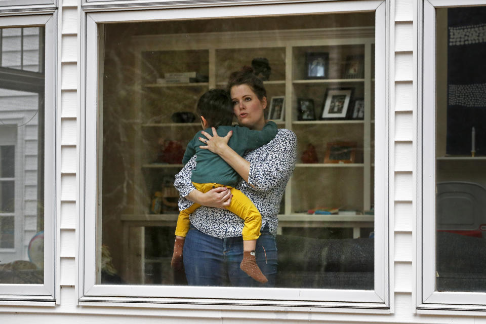 In this Wednesday, April 1, 2020 photo, Joy Engel holds her son at her home in Cape Elizabeth, Maine. Engel, who is pregnant, and her husband, Dr. Ben Hagopian, who works at a family practice and an urgent care clinic, decided to isolate themselves from each since the coronavirus outbreak. (AP Photo/Robert F. Bukaty)