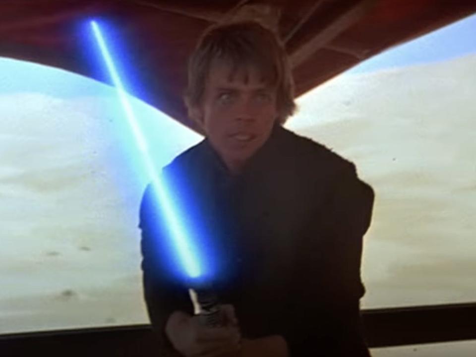 Luke Skywalker (Mark Hamill) holding a blue lightsaber on Jabba's Barge.