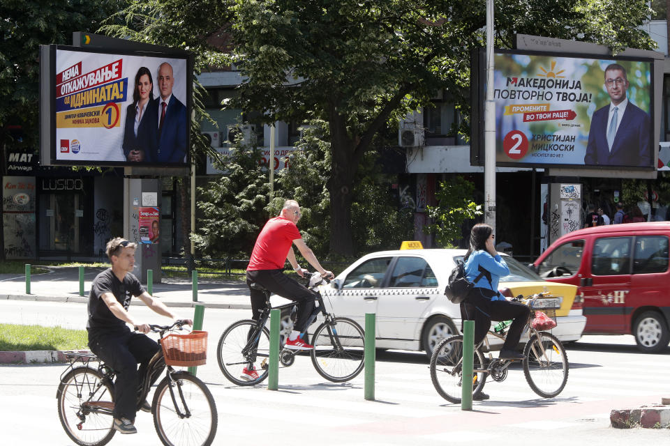 People ride bicycles near election posters of Dimitar Kovacevski, the leader of the ruling Social-Democrats (SDSM) with Monika Zajkova, Liberal-Democrat from the same coalition, left and Hristijan Mickoski, the leader of the center-right main opposition VMRO-DPMNE party, right, in a street in Skopje, North Macedonia, on Monday, May 6, 2024. Voters go to the polls on Wednesday in North Macedonia to cast ballots for parliamentary election and presidential runoff, for the second time in two weeks. (AP Photo/Boris Grdanoski)