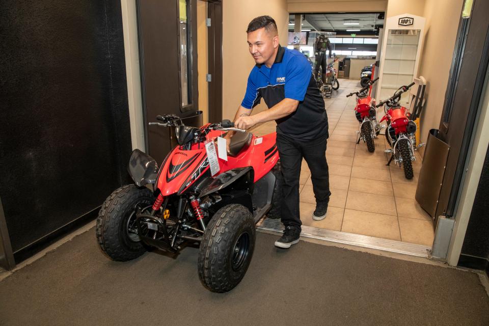 Coyne Powersports employee Armando Berdusco pushes a newly purchased all-terrain vehicle from the showroom to the shop in preparation for delivery to a customer at the store in El Centro, Calif., on July 8, 2021. Berdusco of El Centro has worked at the growing local business for the past four years.