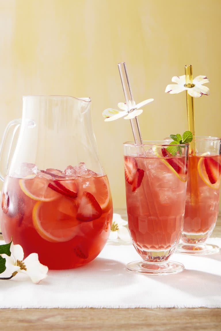 dogwood punch in a pitcher and glasses with ice and sliced strawberries and lemons