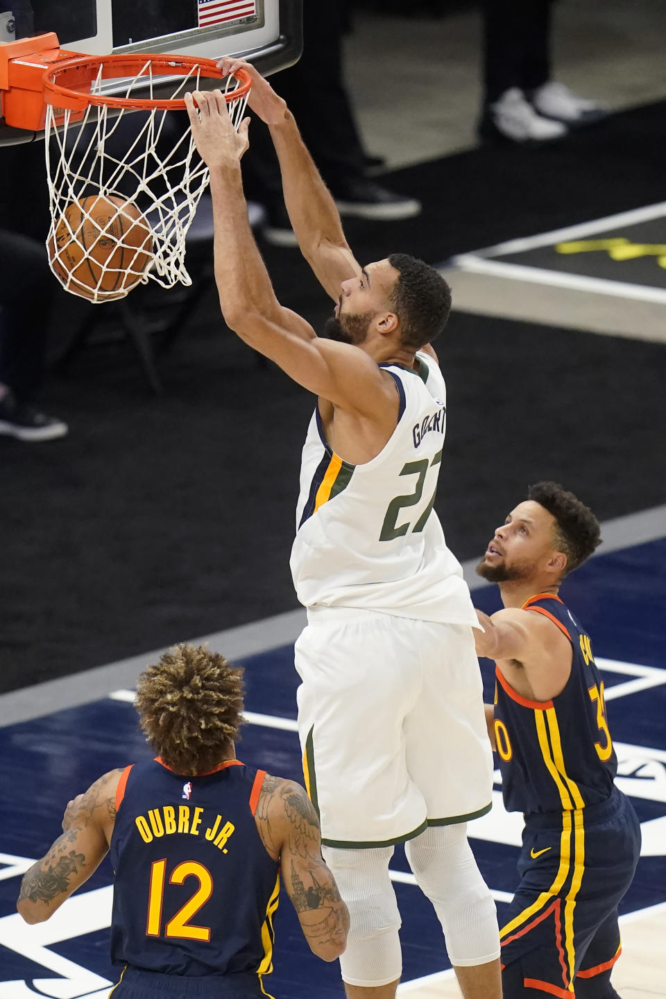 Utah Jazz center Rudy Gobert (27) dunks as Golden State Warriors' Kelly Oubre Jr. (12) and Stephen Curry, right, defend during the first half of an NBA basketball game Saturday, Jan. 23, 2021, in Salt Lake City. (AP Photo/Rick Bowmer)