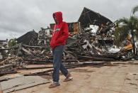 A man walks past the ruin of a government building damaged by an earthquake in Mamuju, West Sulawesi, Indonesia, Saturday, Jan. 16, 2021. Damaged roads and bridges, power blackouts and lack of heavy equipment on Saturday hampered Indonesia's rescuers after a strong and shallow earthquake left a number of people dead and injured on Sulawesi island. (AP Photo/Joshua Marunduh)