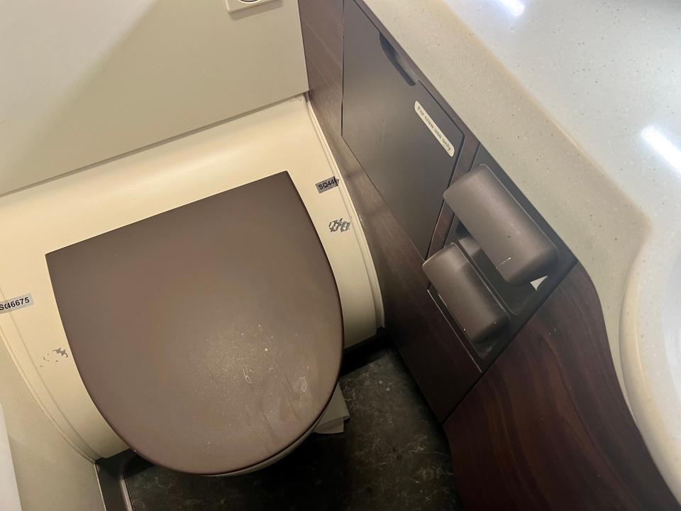 The lavatory with the toilet seat down. The space is brown and white.