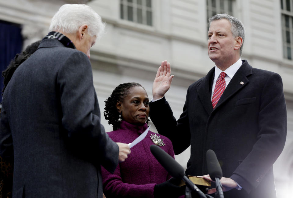 FILE - In this Jan. 1, 2014, file photo, Mayor-elect Bill de Blasio, right, takes the oath of office administered by former President Bill Clinton, left, while de Blasio's wife, Chirlane McCray, center, holds the bible for her husband during his public inauguration ceremony at City Hall in New York. De Blasio's first 100 days as mayor of New York City were marked in nearly equal measures by accomplishing campaign goals and committing political blunders. (AP Photo/Seth Wenig, File)
