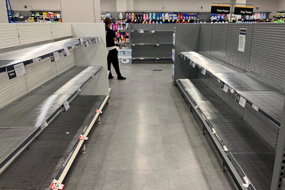 A customer walks past two empty shelves in Woolworths. 