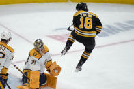 Boston Bruins center Pavel Zacha (18) leaps out of the way of the puck as Nashville Predators goaltender Juuse Saros (74) makes a save during the second period of an NHL hockey game Tuesday, March 28, 2023, in Boston. (AP Photo/Charles Krupa)