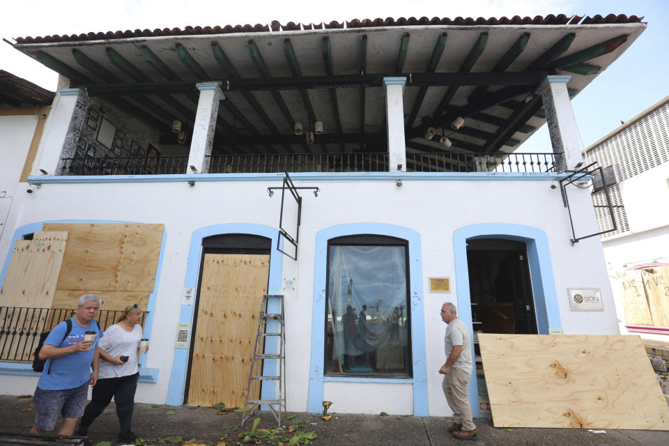 Residents remove protection from the windows at a restaurant after the passing of Hurricane Lidia in Puerto Vallarta, Mexico, Wednesday, Oct. 11, 2023. Lidia dissipated Wednesday after hitting land as a Category 4 hurricane. (AP Photo/Valentin Gonzalez)