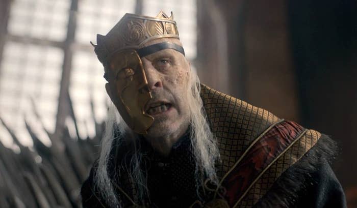 Viserys with a half mask made of gold, wearing the crown