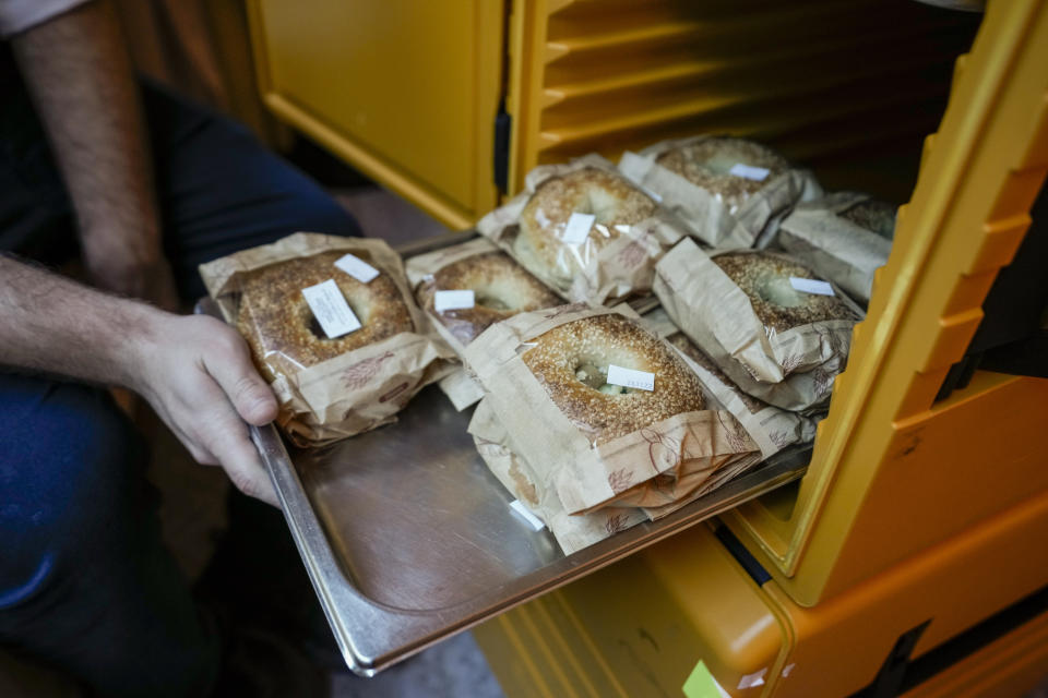 Eli Chitrik from Turkey shows bagel sandwiches at his hotel room in Doha, Qatar, Monday, Nov. 28, 2022. Stored into bright orange cases in Rabbi Eli Chitrik’s hotel room are bagels stuffed with vegetables. The labels declare the sandwiches kosher, or in compliance with Judaism’s set of dietary regulations. Freshly baked, they are made in Qatar at a designated kitchen, set up to feed Jewish World Cup visitors who want to keep kosher during the tournament. (AP Photo/Moises Castillo)