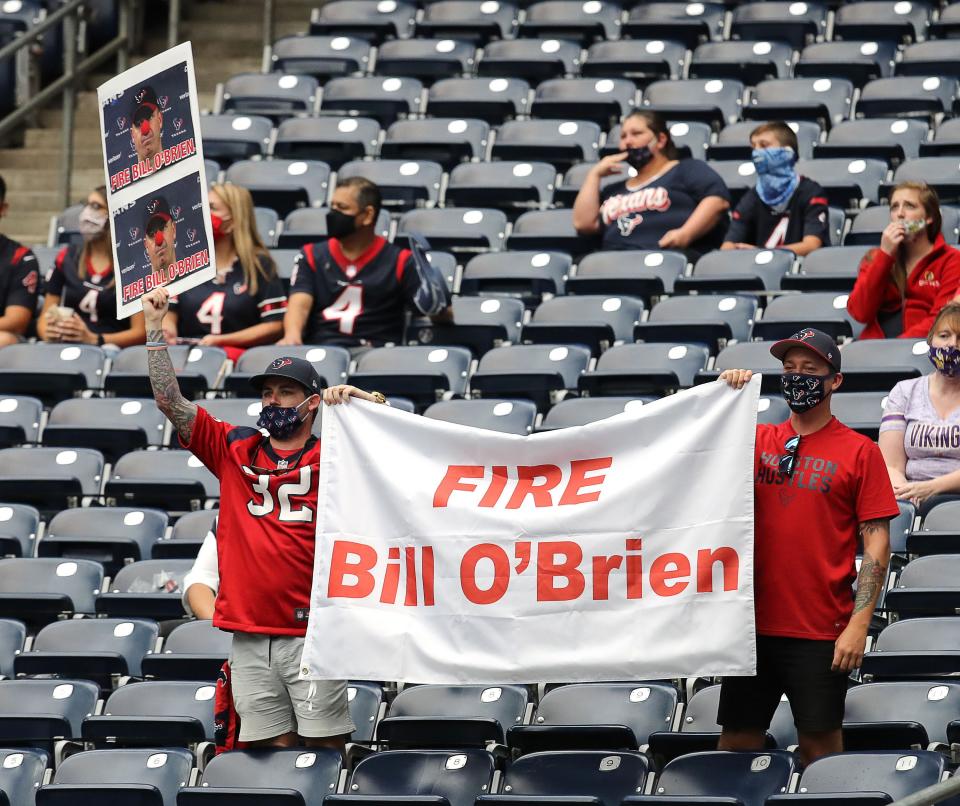 Texans fans hold up a "Fire Bill O'Brien" banner while wearing masks.