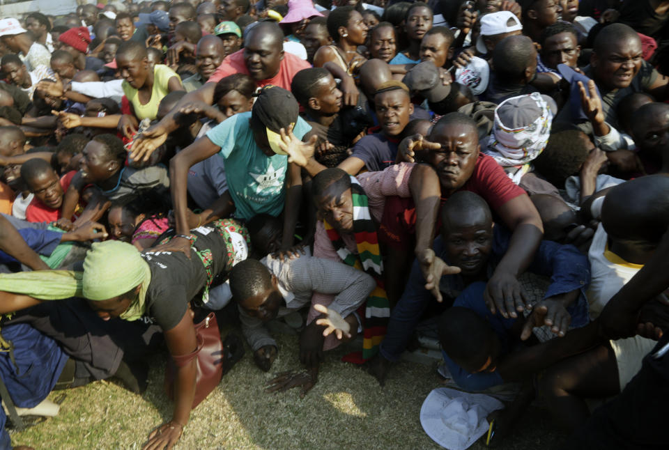Mourners stampede after the arrival of the coffin carrying former President Robert Mugabe at the Rufaro Stadium in Harare, Thursday, Sept. 12, 2019 where Mugabe will lie in state for a public viewing. Mugabe, the founder leader, made his final journey back to the country Wednesday amid continuing controversy over where he will be buried. (AP Photo/Themba Hadebe)