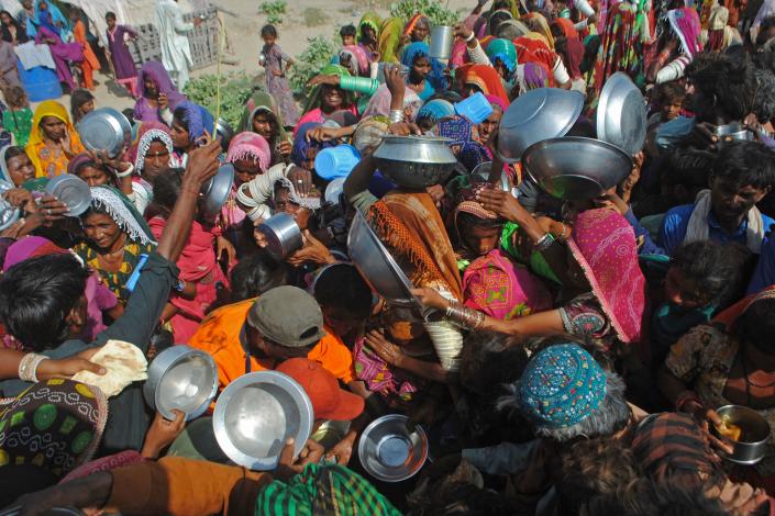 Internally displaced people gather to receive free food near their makeshift camp in the flood-hit Chachro of Sindh province on September 19, 2022. (-/AFP via Getty Images)