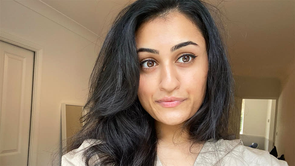 Jaya Pathak, an Asian woman, looking at the camera taking a selfie. She is indoors with light plain walls.