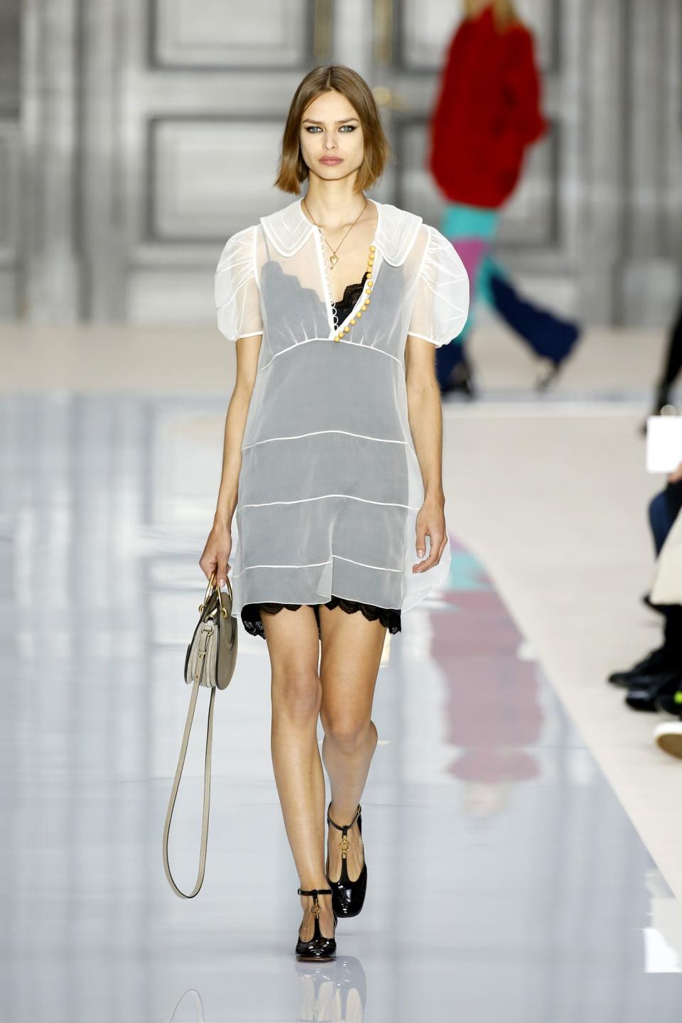 Model wears a black silk slip underneath a sheer white dress at the Chloé Fall/Winter 2017 show