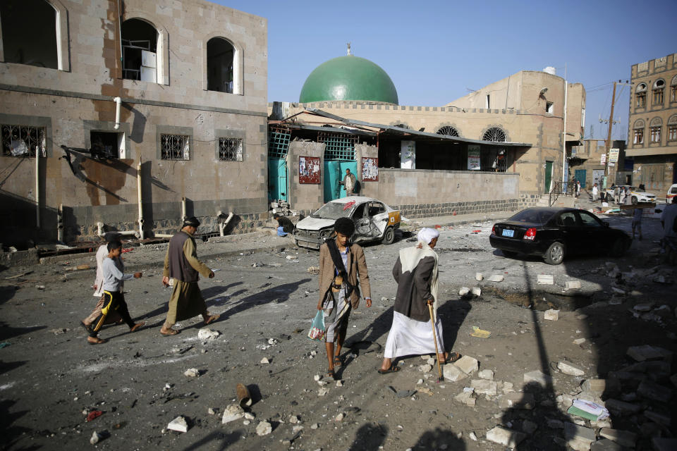 FILE - In this Sept. 3, 2015, file photo people walk at the site of a car bomb attack next to a Shiite mosque in Sanaa, Yemen. Yemen’s civil war has exacted an enormous toll on people with disabilities, who find themselves on the margins of society and excluded from badly needed humanitarian assistance, Amnesty International said in a report released Tuesday, Dec. 3, 2019. (AP Photo/Hani Mohammed, File)