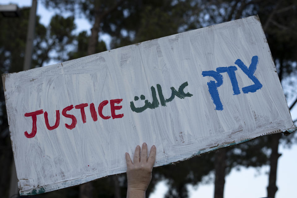 FILE - A Israeli woman holds a placard that reads, "Justice," in English, Farsi and Hebrew during a protest in solidarity with Mahsa Amini, a young Iranian woman who died after being arrested in Tehran by Iran's notorious morality police, in central Jerusalem, Thursday, Oct. 6, 2022. As anti-government protests roil cities and towns in Iran for a fourth week, sparked by the death of Amini, tens of thousands of Iranians living abroad have marched on the streets of Europe, North America and beyond in support of what many believe to be a watershed moment for their home country. (AP Photo/ Maya Alleruzzo, File)
