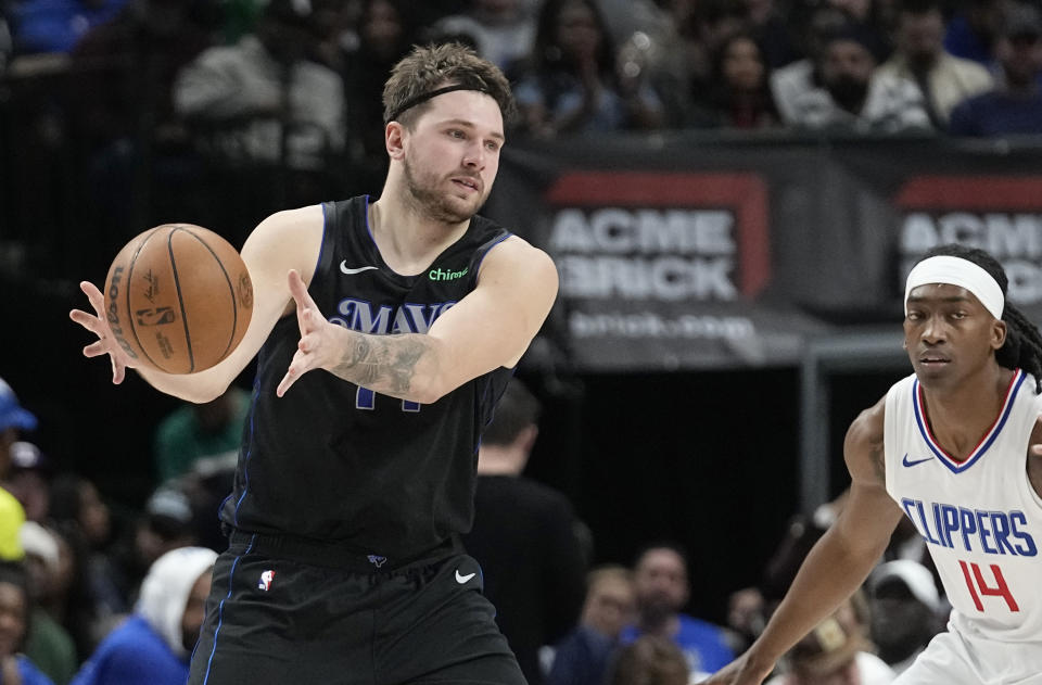 Dallas Mavericks guard Luka Doncic (77) grabs a pass in front of Los Angeles Clippers guard Terance Mann (14) during the first half of an NBA basketball game in Dallas, Wednesday, Dec. 20, 2023. (AP Photo/LM Otero)