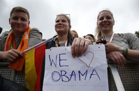 People hold posters as they attend a discussion by German Chancellor Angela Merkel and former U.S. President Barack Obama. REUTERS/Fabrizio Bensch