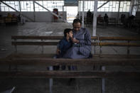 A man sits with this son inside the government passport office which re-opened after the Taliban announced they would be issuing a backlog of applications approved by the previous administration in Kabul, Afghanistan, Sunday, Oct. 17, 2021. (AP Photo/Ahmad Halabisaz)