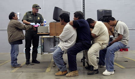 A man has his fingerprints electronically scanned by a U.S. Border Patrol agent while others wait for their turn at the U.S. Border Patrol detention center in Nogales, Arizona, May 31, 2006. REUTERS/Jeff Topping/File Photo