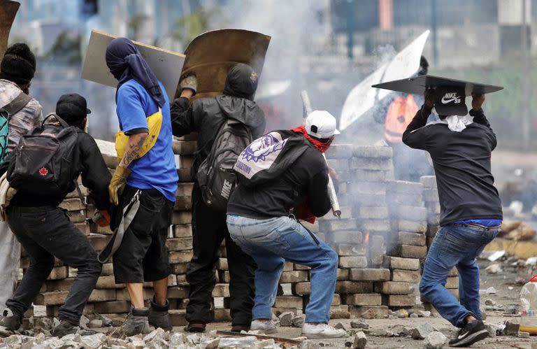 Manifestantes se parapetan detrás de una barricada en los choques con la policía en Quito