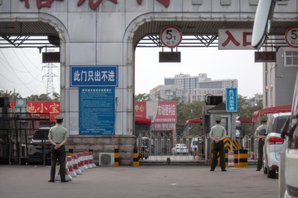 Chinese paramilitary police stand guard at barricaded entrances to the Xinfadi wholesale food market district in Beijing, Saturday, June 13, 2020. Beijing closed the city's largest wholesale food market Saturday after the discovery of seven cases of the new coronavirus in the previous two days. (AP Photo/Mark Schiefelbein)