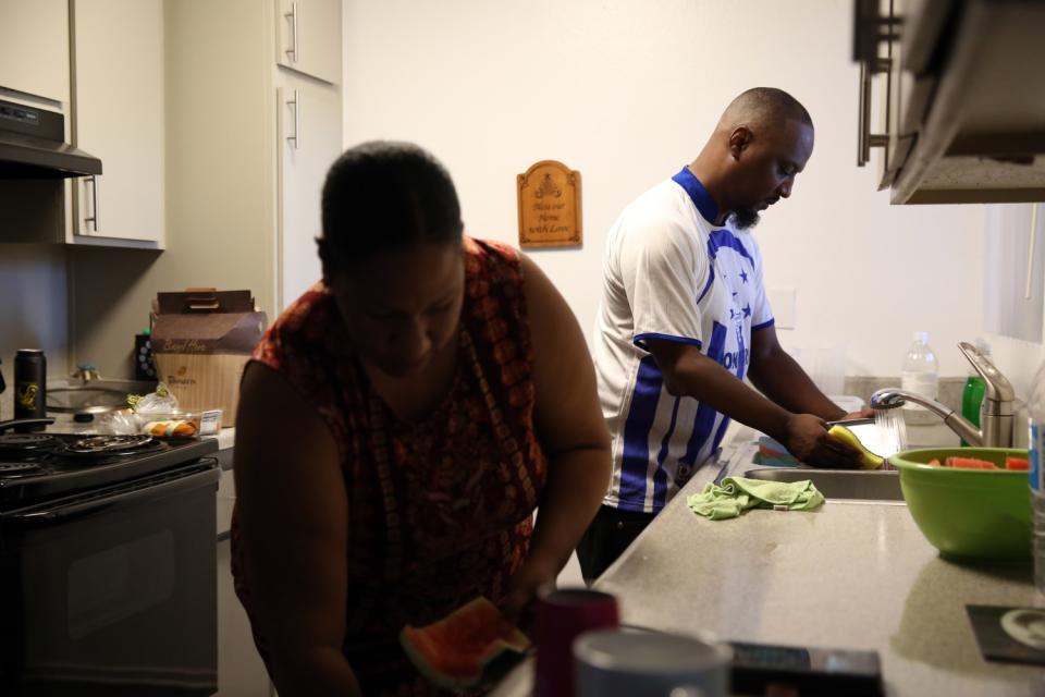 A couple wash dishes in their apartment