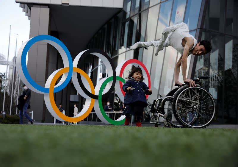 Kenta Kambara, de 34 años, posa para una foto mientras su hija Shiori, de 2 años, pasa junto a él, junto a un símbolo de los Anillos Olímpicos frente al Museo Olímpico de Japón en Tokio