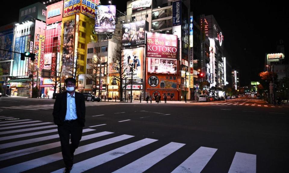 A man wearing a face mask walks across the road in the Akihabara district of Tokyo.