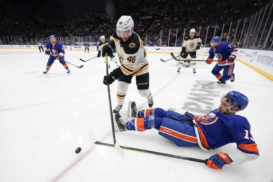 Boston Bruins' Matt Grzelcyk (48) reaches for the puck next to fallend New York Islanders' Mathew Barzal (13) during the second period of Game 3 during an NHL hockey second-round playoff series Thursday, June 3, 2021, in Uniondale, N.Y. (AP Photo/Frank Franklin II)