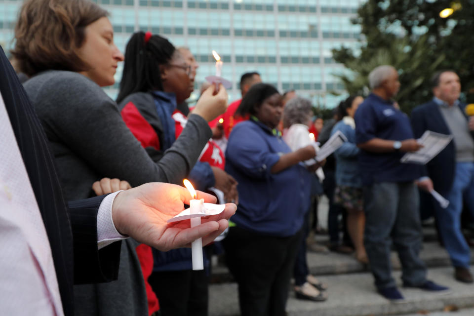 People hold candles during a candlelight vigil outside city hall for deceased and injured workers from the Hard Rock Hotel construction collapse Sat., Oct. 12, in New Orleans, on Thursday, Oct. 17, 2019. The vigil was organized by various area labor groups. (AP Photo/Gerald Herbert)