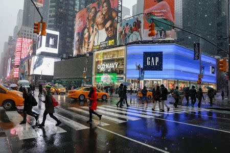 People walk through the snow during a winter nor'easter storm in Times Square in New York City, U.S., March 21, 2018. REUTERS/Brendan McDermid