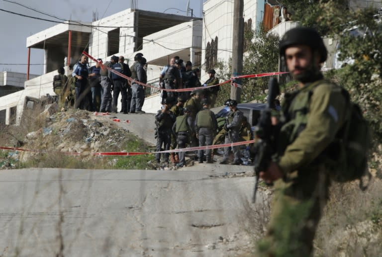 An Israeli security forces stand guard as his comrades gather around the body of a Palestinian who rammed his car into Israeli soldiers in Beit Omar, near the West Bank city of Hebron, on November 27, 2015