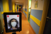 Nurse Helga drives 'Ivo' a tablet supported by a periscopic pole mounted on wheels at 'Ospedale di Circolo' in Varese, Italy, Wednesday, April 8, 2020. Ivo is remotely controlled by the healthcare professional via smartphone. It can enter the rooms and, with a video call system, put the staff in communication with the patients. The new coronavirus causes mild or moderate symptoms for most people, but for some, especially older adults and people with existing health problems, it can cause more severe illness or death. (AP Photo/Luca Bruno)