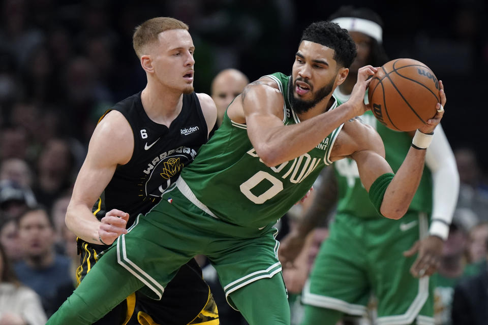 Jayson Tatum, alero de los Celtics de Boston, controla el balón frente a Donte DiVincenzo, de los Warriors de Golden State, el jueves 19 de enero de 2023 (AP Foto/Steven Senne)