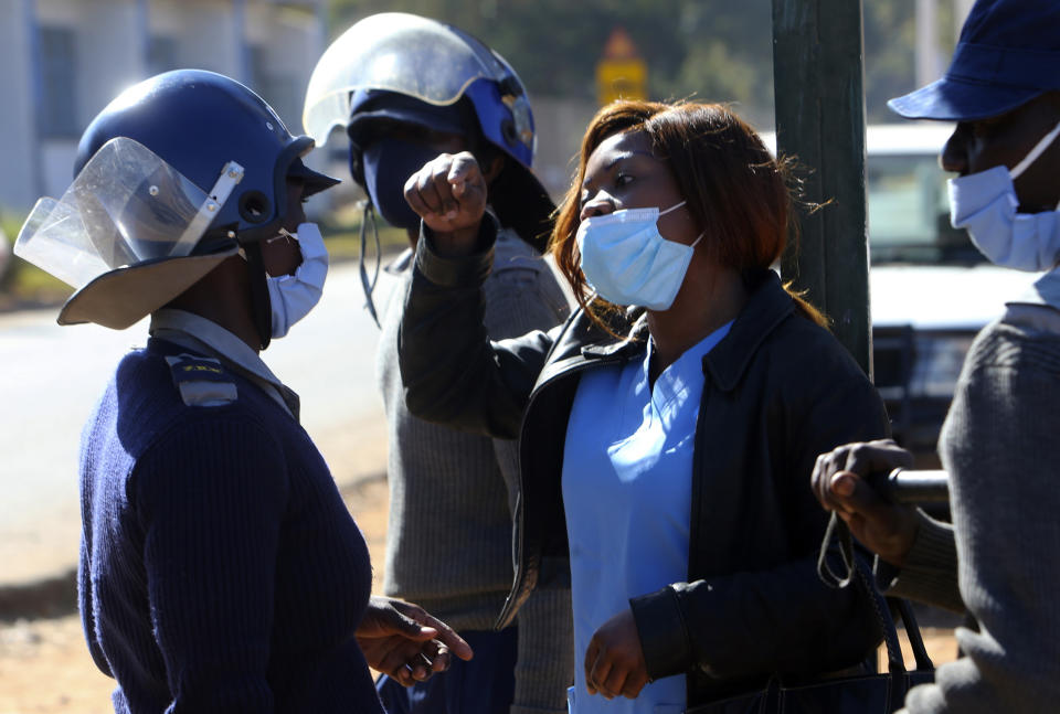 Riot police surround a nurse who was protesting at a government hospital in Harare, Monday, July, 6, 2020. Thousands of nurses working in public hospitals stopped reporting for work in mid-June, part of frequent work stoppages by health workers who earn less than $50 a month and allege they are forced to work without adequate protective equipment. On Monday, dozens of nurses wearing masks and their white and blue uniforms gathered for protests at some of the country’s biggest hospitals in the capital, Harare, and the second-largest city of Bulawayo.(AP Photo/Tsvangirayi Mukwazhi)