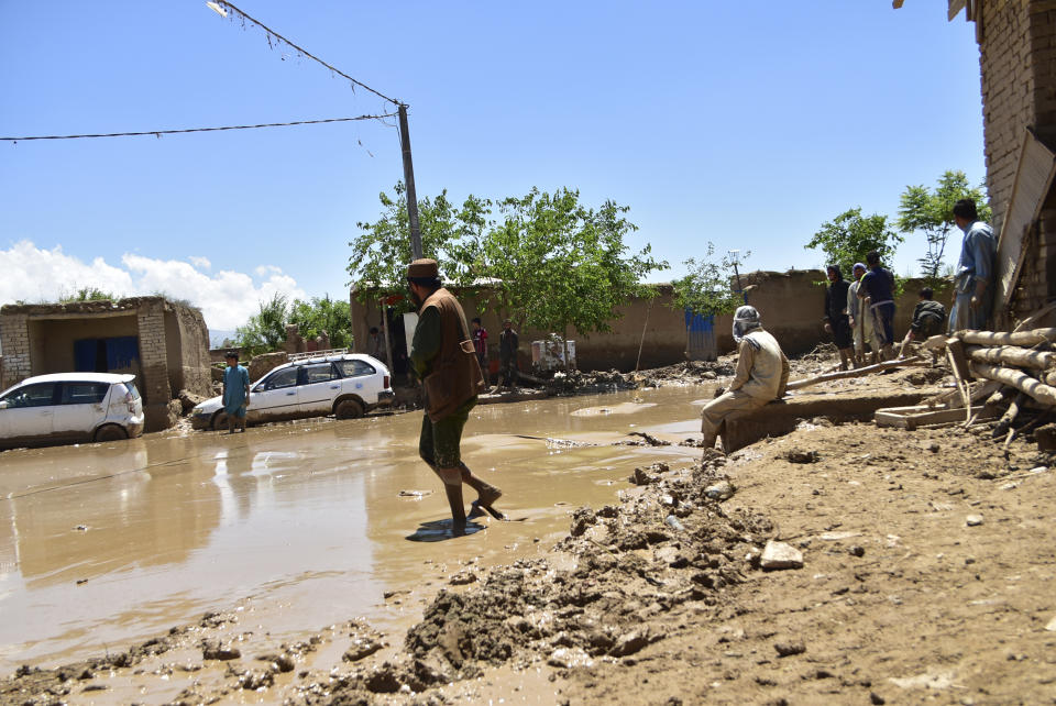 People stand in muddy water after heavy flooding in Baghlan province, in northern Afghanistan, Sunday, May 12, 2024. Victims of the devastating floods in northern Afghanistan are burying the dead and looking for the loved ones still missing. (AP Photo)