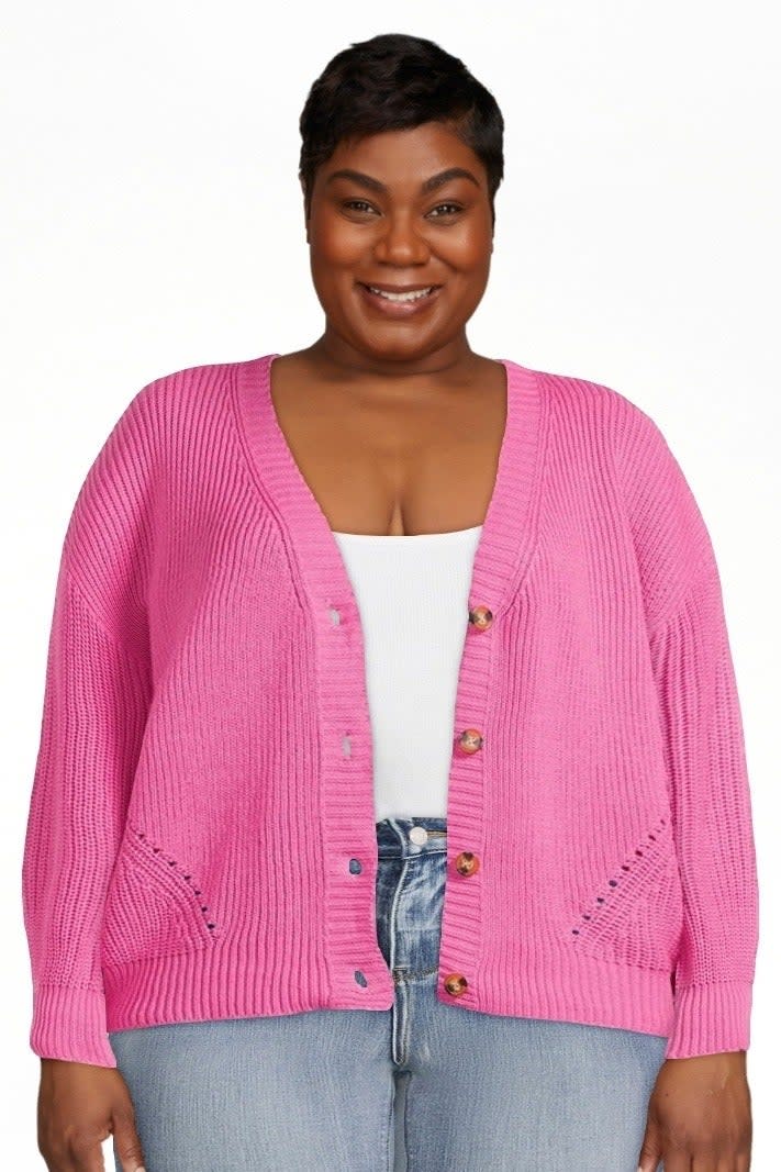 model in plus-size pink cardigan and jeans, with a white top, smiling at the camera