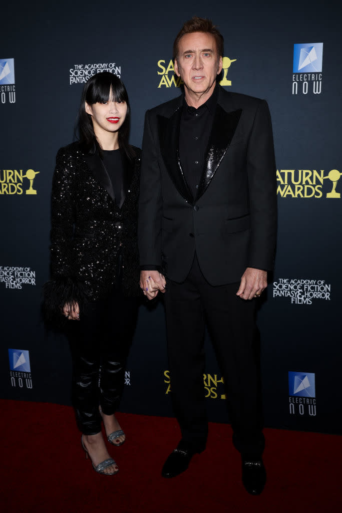 Two celebrities on red carpet; one in a sequined dress, the other in a suit with satin lapels