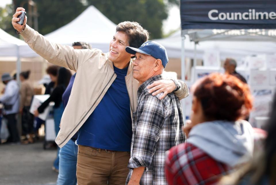 Kevin de León takes a selfie with his arm around a man.