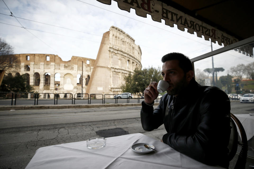 A man sips coffee in front of Rome's ancient Colosseum after its reopening Monday, Feb. 1, 2021, in a partial lifting of restriction measures aimed at containing the spread of COVID-19. Italy has eased its coronavirus restrictions Monday for most of the country downgrading Lazio and other regions from medium-risk orange zones to lower-risk yellow zones. (Cecilia Fabiano /LaPresse via AP)