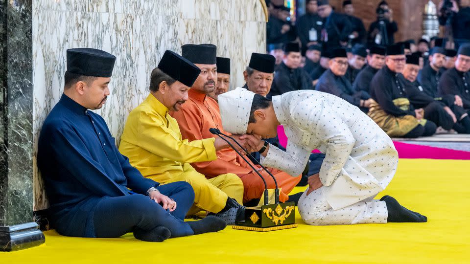 Prince Mateen kneels before his father, Sultan Hassanal Bolkiah, after the solemnization ceremony. - Brunei's Information Department/AP