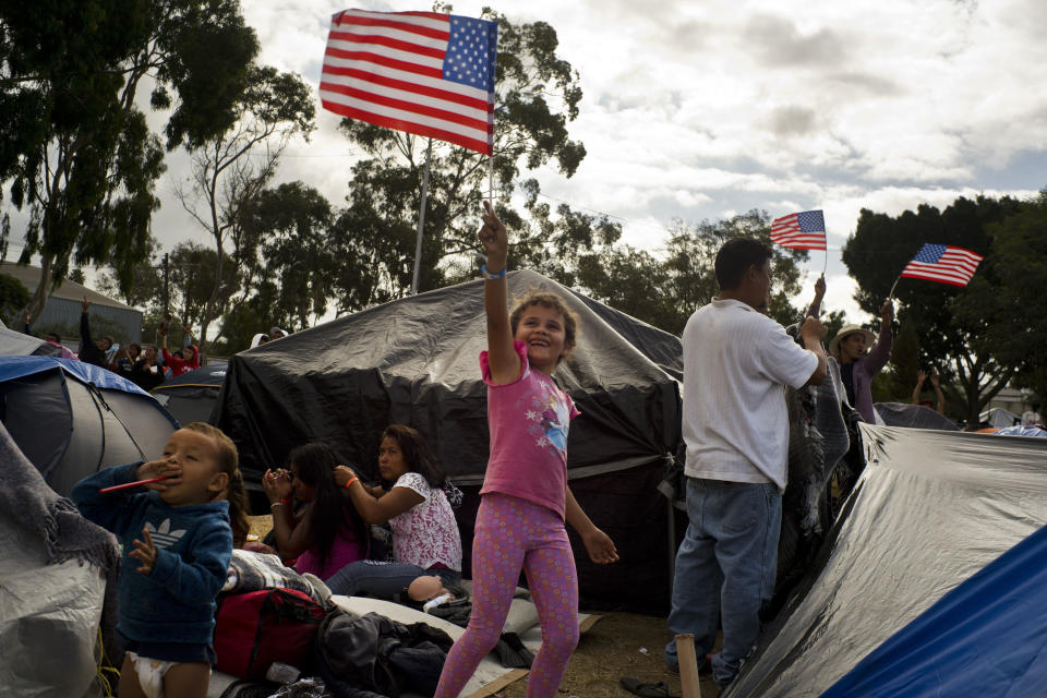 Seven-year-old Honduran migrant Genesis Belen Mejia Flores waves an American flag at two U.S. border control helicopters flying overhead near a shelter in Tijuana, Mexico. (Photo: ASSOCIATED PRESS)