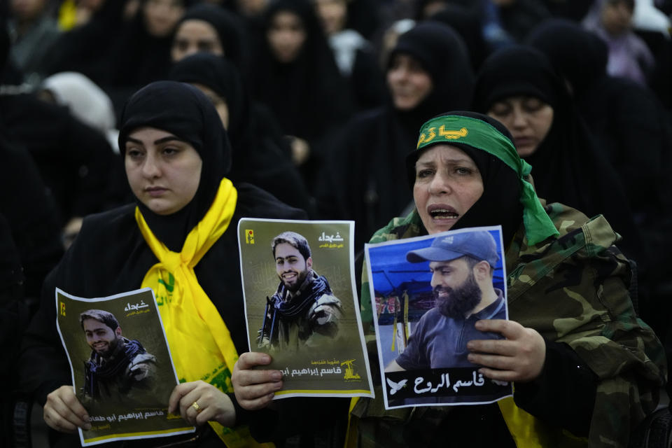 The mother of Hezbollah fighter, Qassim Ibrahim Abu-Taam, right, who was killed along Lebanon's southern border with Israel, holds her son's portraits during his funeral procession in the southern Beirut suburb of Dahiyeh, Lebanon, Monday, Nov. 6, 2023. (AP Photo/Hassan Ammar)