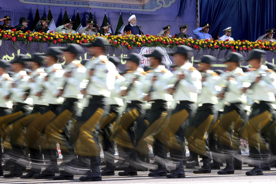 ADDS THAT ATTACK WAS ON A DIFFERENT MILITARY PARADE IN THE SOUTHWESTERN CITY OF AHVAZ - Iran's President Hassan Rouhani, top center, reviews army troops marching during the 38th anniversary of Iraq's 1980 invasion of Iran, in front of the shrine of the late revolutionary founder, Ayatollah Khomeini, outside Tehran, Iran, Saturday, Sept. 22, 2018. Elsewhere gunmen disguised as soldiers attacked the annual parade in the southwestern city of Ahvaz, killing dozens of people and wounding others in the bloodiest assault to strike the country in recent years. (AP Photo/Ebrahim Noroozi)