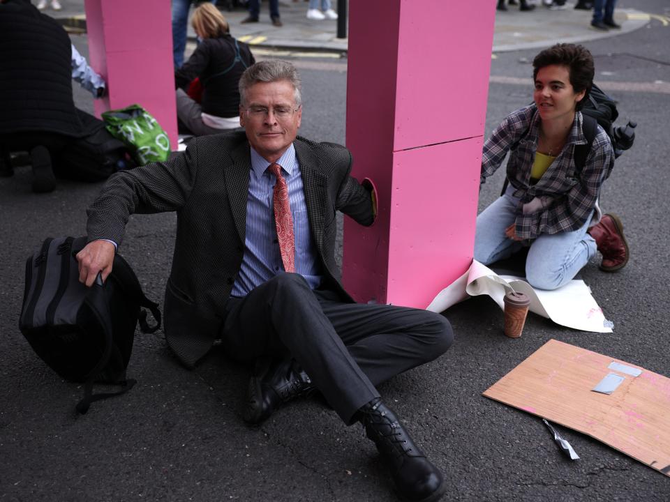 Protestors lock their arms into the giant pink table to stop police from removing it (Getty)